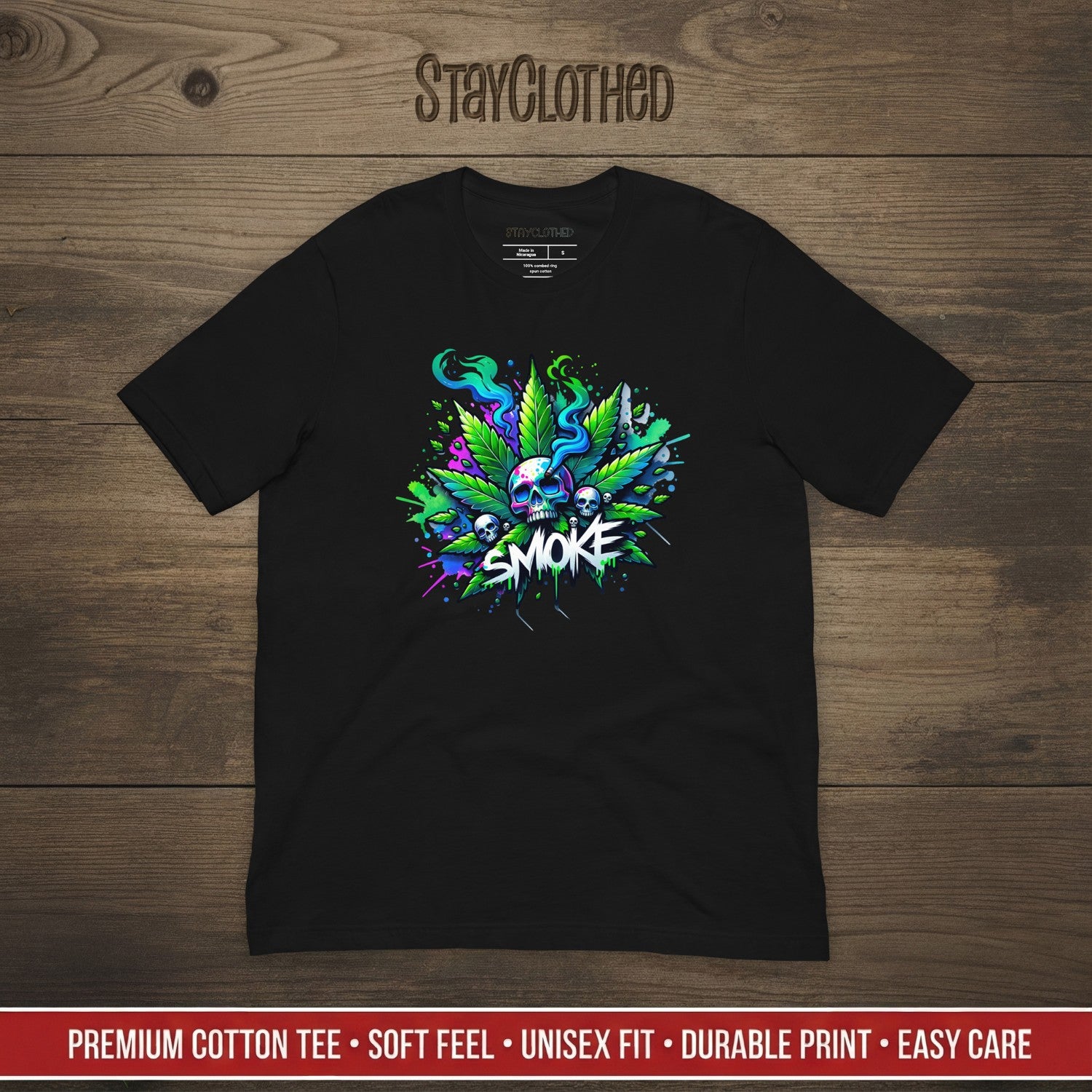 Black t-shirt with colorful cannabis graphic design on a wooden surface, featuring the brand 'StayClothed'.