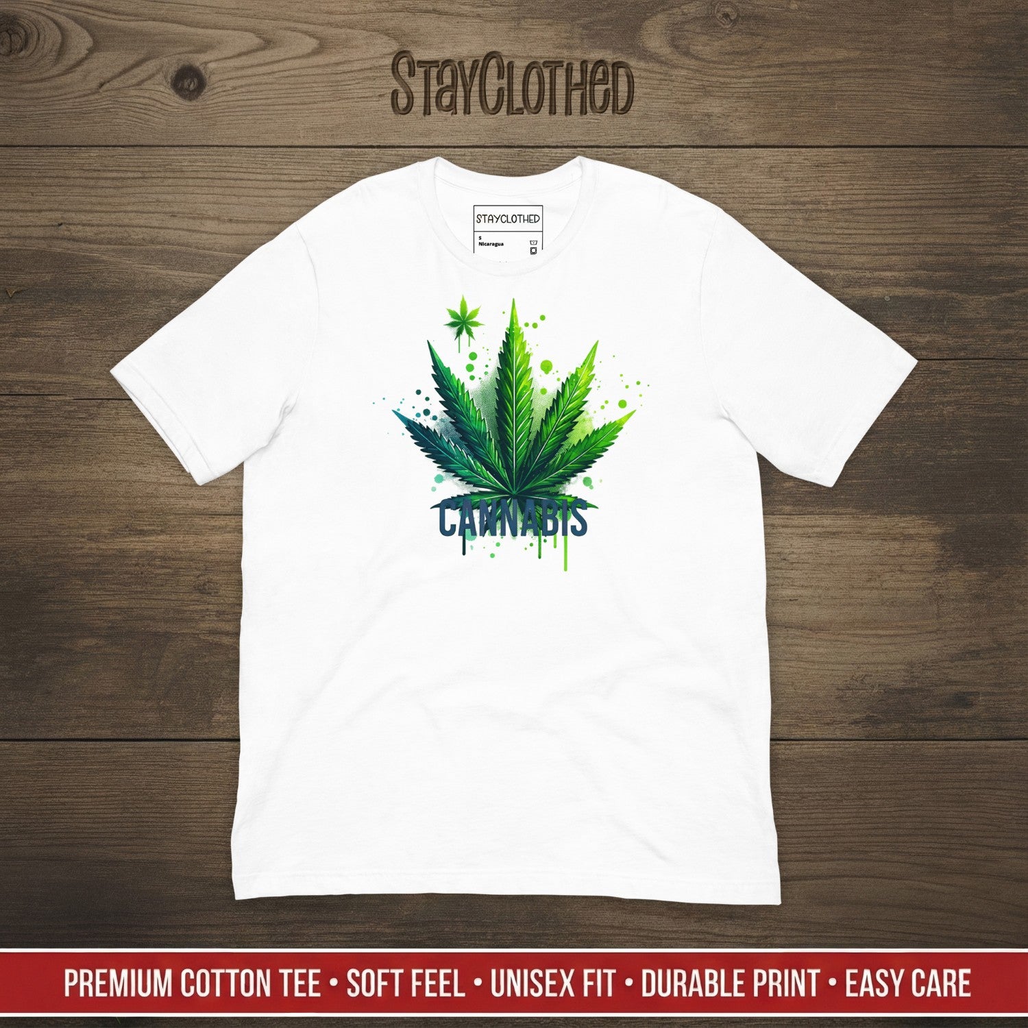 White t-shirt with cannabis leaf graphic on a wooden surface, featuring 'StayClothed' brand.