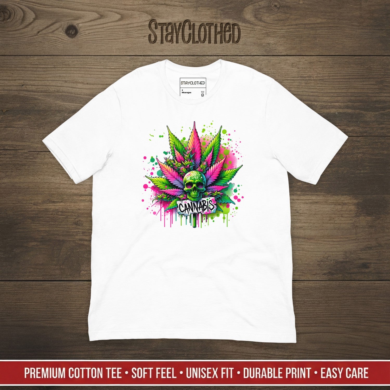 White t-shirt with colorful cannabis leaf design on a wooden surface, featuring 'StayClothed' brand.