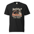 Front view of a black T-shirt featuring a cosy dachshund wrapped in a blanket beside a steaming mug, with the text “Anxiety?”