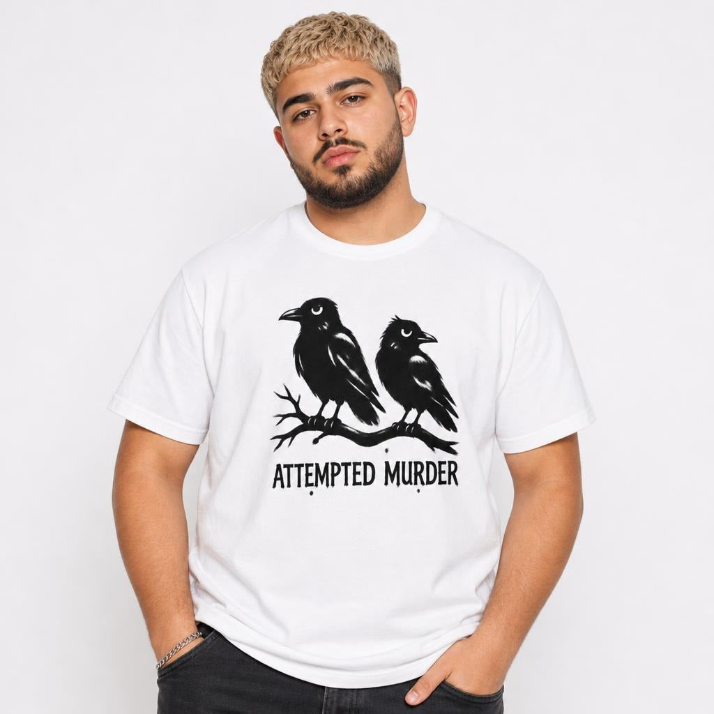 Front view of a person wearing a white T-shirt with two black crows perched on a branch above the words “ATTEMPTED MURDER.”