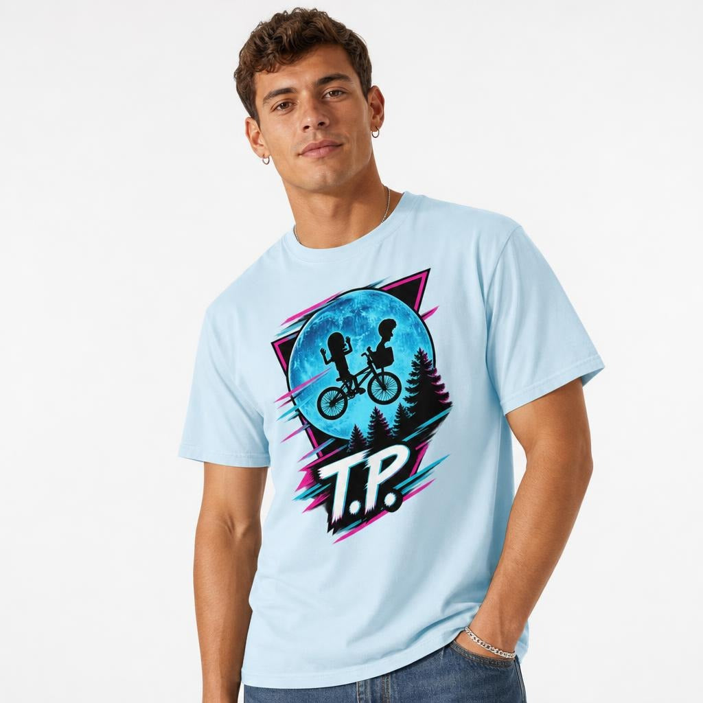 Model wearing a chambray T-shirt with two children riding a bicycle before a blue moon, pine trees, neon accents and T.P. lettering.