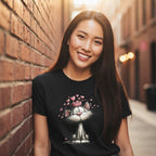 Woman wearing a black t-shirt with a cartoon cat design, standing against a brick wall.