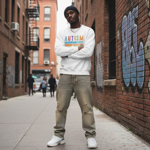 Black man wearing a white autism awareness sweatshirt with Accept, Understand, Love, and Different design.