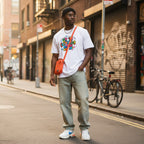 Black man wearing a white be kind autism awareness puzzle piece doodle t-shirt.