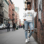 Black woman wearing a white autism skeleton puzzle sweatshirt.