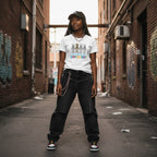 Black woman wearing a white autism awareness skeleton puzzle t-shirt.