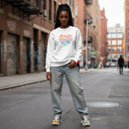 Black woman wearing a white "Celebrate Minds of All Kinds" floral heart sweatshirt.