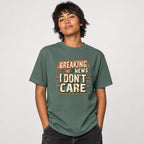 Breaking News I Dont Care t shirt in Blue Spruce worn by a studio model in an upper-body hands in pockets pose on a clean white background