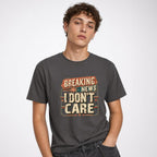 Breaking News I Dont Care t shirt in Graphite worn by a studio model in an upper-body three quarter left pose on a clean white background