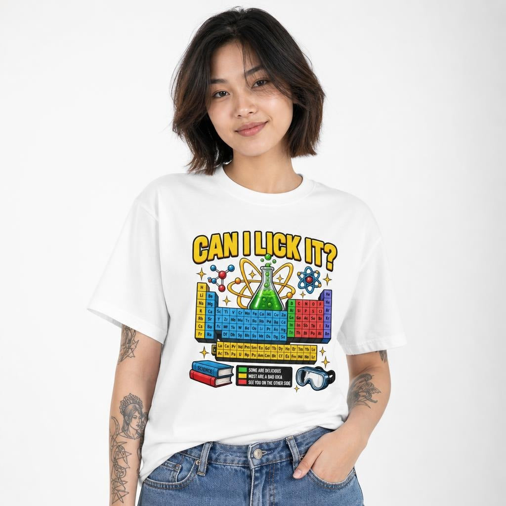 Front view of a white T-shirt featuring “CAN I LICK IT?” above a colourful periodic table, chemistry flask and atom artwork.