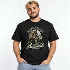 Model wearing a black T-shirt with a vintage-style Sasquatch walking through mountains and pine trees, with “DON’T BE AN Assquatch” text.