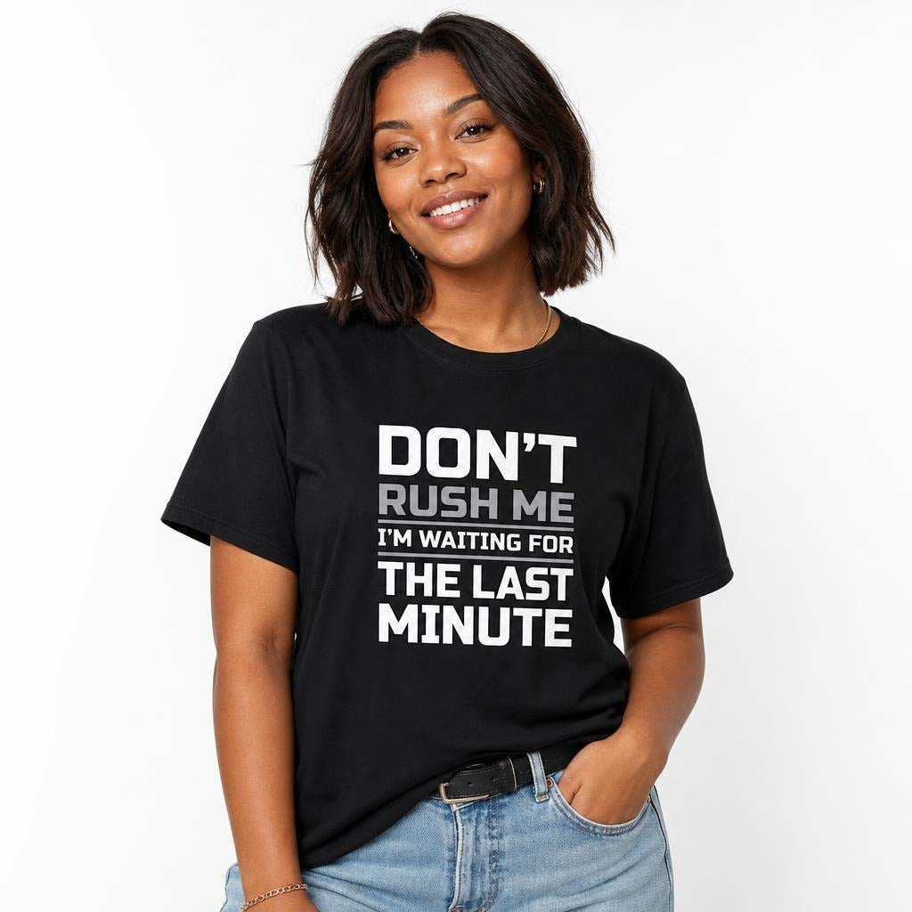 Front view of a person wearing a black T-shirt with a bold white and grey slogan reading “DON’T RUSH ME, I’M WAITING FOR THE LAST MINUTE.”