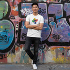 East Asian man wearing a white t-shirt with a puzzle heart design.