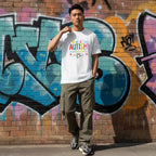East Asian man wearing a white autism awareness T-shirt in a streetwear style.