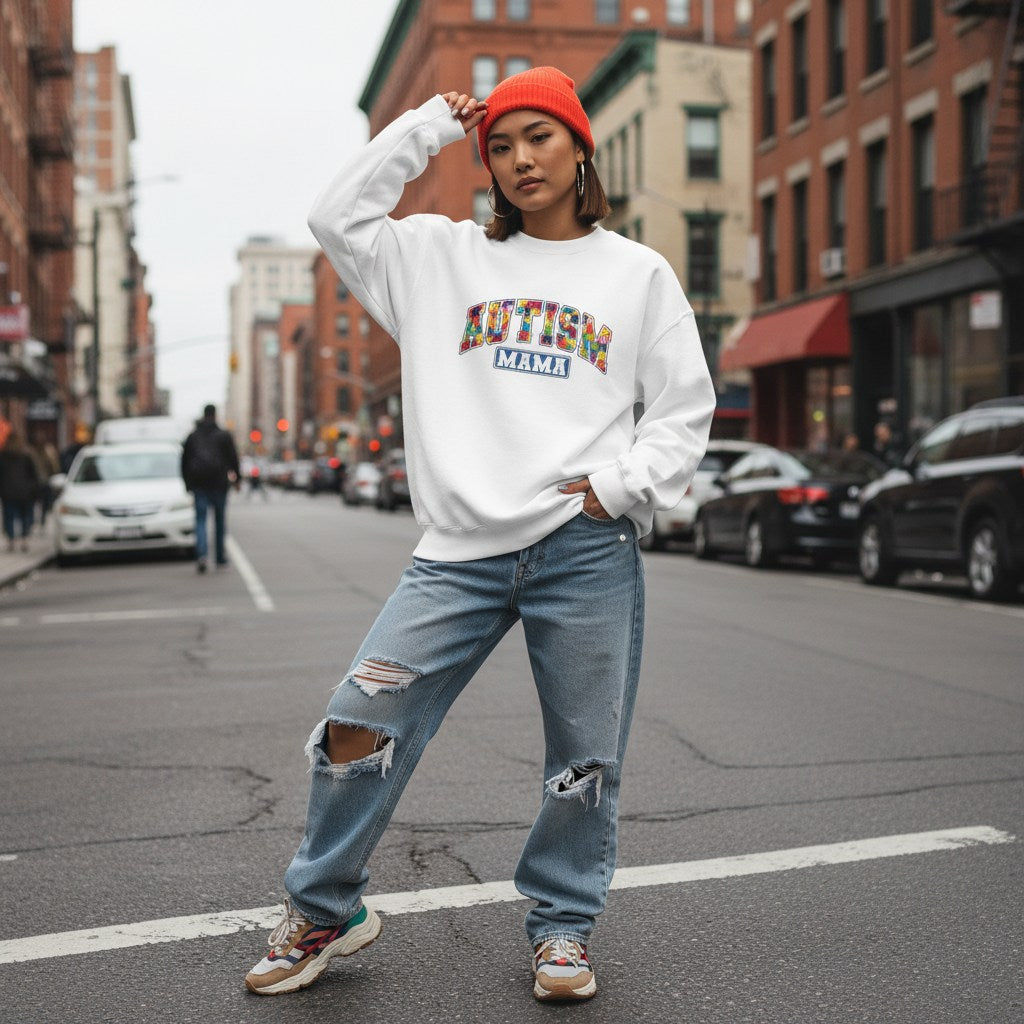 East Asian woman wearing a white autism mama collegiate sweatshirt.