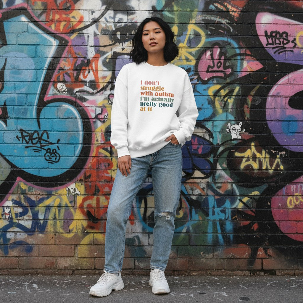 East Asian woman wearing a white I Don't Struggle With Autism sweatshirt.