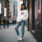 East Asian woman wearing a white puzzle bow sweatshirt in a streetwear style.