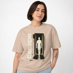 Model wearing a Sand T-shirt featuring a human silhouette in a corridor with a wireframe sphere and geometric accents.