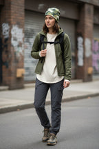 Person wearing a green jacket, white shirt, and gray pants on a street wearing a camo beanie