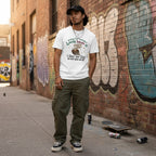 Hispanic man in streetwear leaning against a white background.