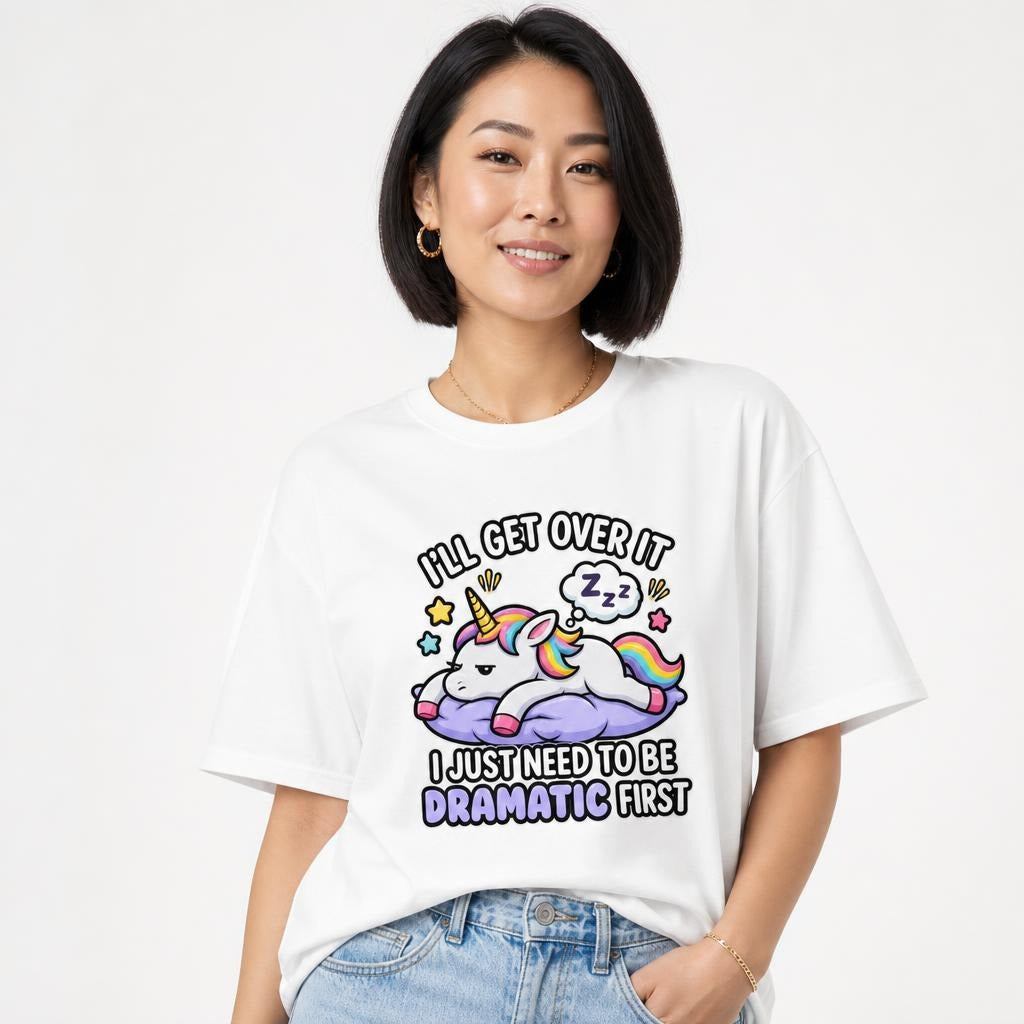 Model wearing a white T-shirt with a colorful cartoon unicorn resting on a purple cloud, stars, rainbow mane, and playful text