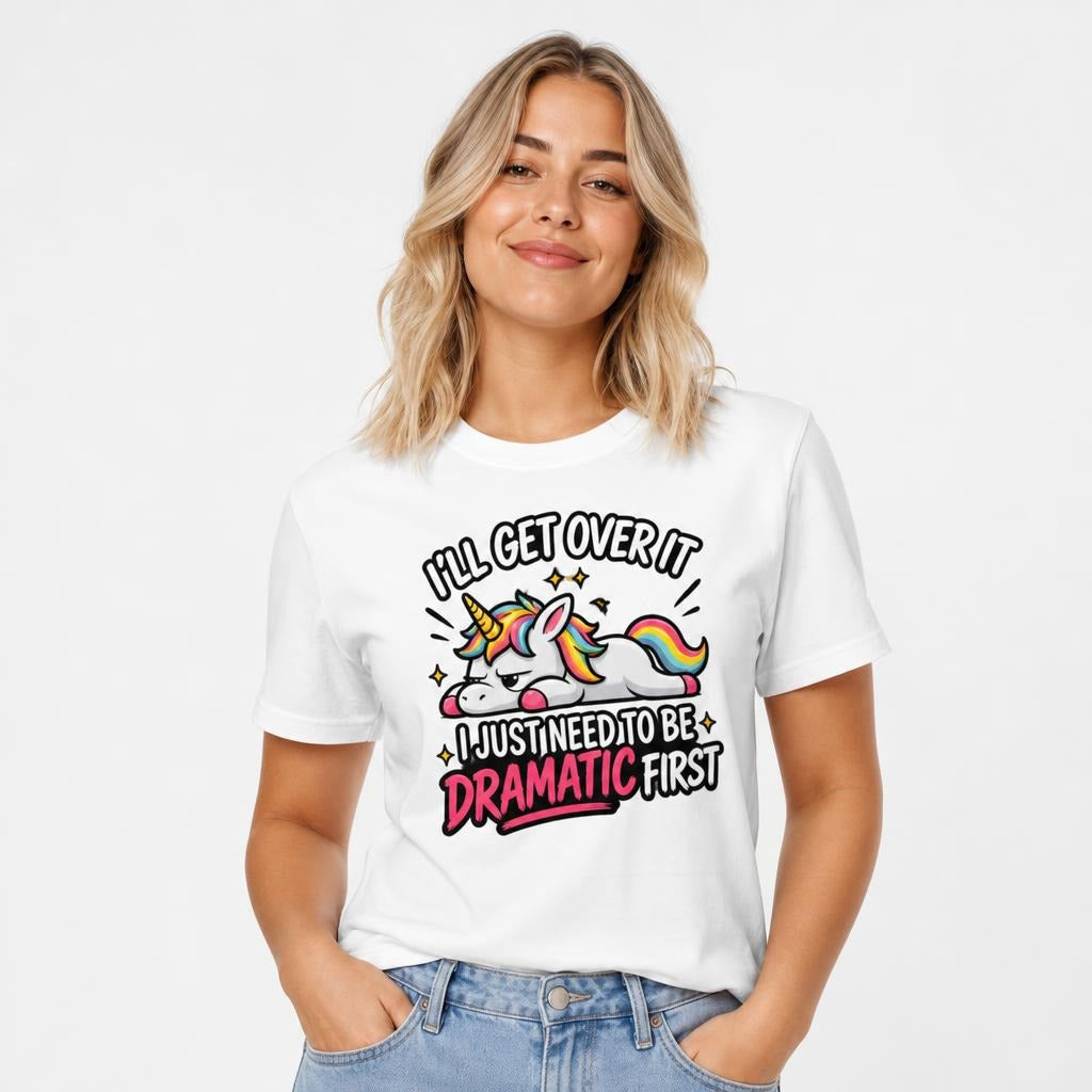 Front view of a model wearing a white T-shirt with a colourful cartoon unicorn and the text “I’LL GET OVER IT I JUST NEED TO BE DRAMATIC FIRST.”