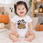 Front view of a baby wearing a white bodysuit with a colorful Halloween character graphic and “My 1st Halloween” text.