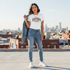 Latina woman wearing a white autism mama collegiate t-shirt.