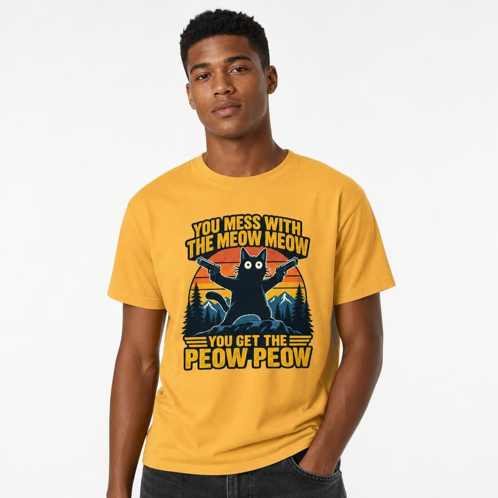 Model wearing a mustard T-shirt featuring a black cat holding two pistols before mountains, with bold yellow wording.