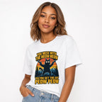 Front view of a white T-shirt featuring a black cat with two pistols, mountains, pine trees, and bold yellow lettering.