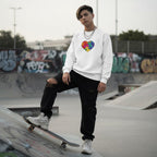 Middle Eastern non-binary person wearing a white rainbow puzzle heart sweatshirt.