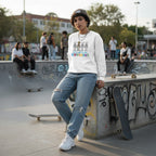 Middle Eastern non-binary person wearing a white autism skeleton puzzle sweatshirt.