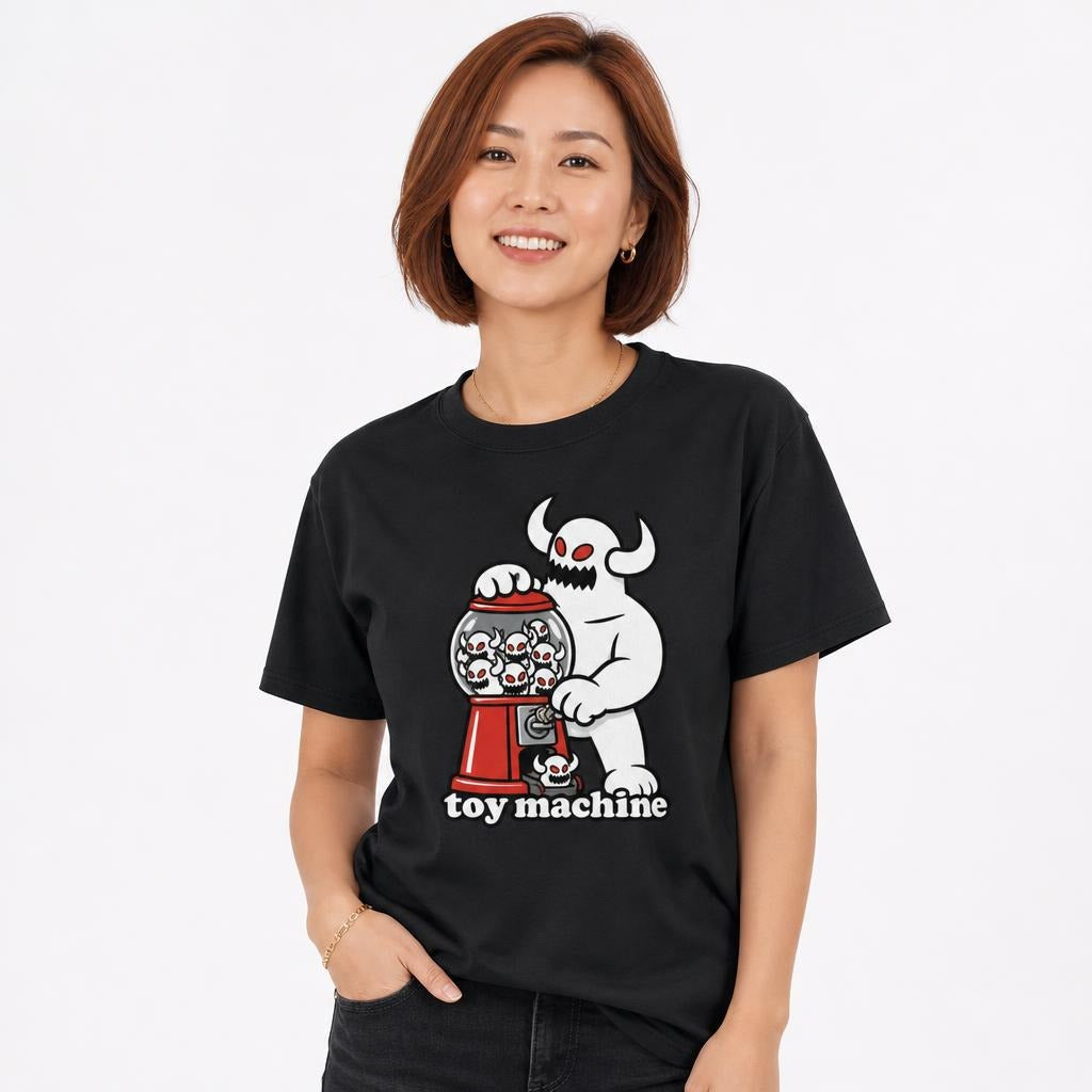 Model wearing a black T-shirt featuring a horned monster operating a red gumball machine filled with skulls, with “toy machine” text.