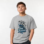 Model wearing a Granite T-Shirt featuring a bandage-wrapped mummy riding a blue skateboard above bold “STAY BOARDIN’” lettering.