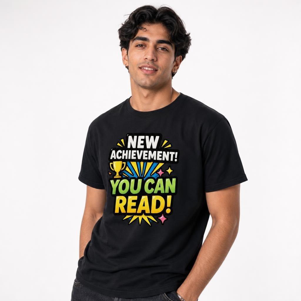 Front view of a person wearing a black T-shirt with a colourful trophy and motivational text reading “NEW ACHIEVEMENT! YOU CAN READ!”