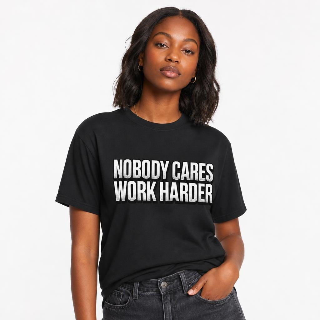 Model wearing a black T-shirt with distressed white text reading “NOBODY CARES WORK HARDER,” a sarcastic work humour design.