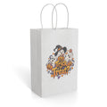 White paper gift bag featuring a colorful Halloween Trick or Treat design with a ghost, witch hat, pumpkins, and candy