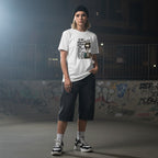 Non-binary person in urban streetwear wearing a white t-shirt with a skeleton girl design.