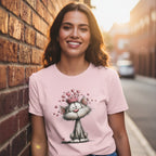 Woman wearing a pink t-shirt with a cat graphic against a brick wall.