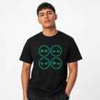 Model wearing a black T-shirt with a four-panel pixel-art graphic of four alien faces with varied expressions in green.