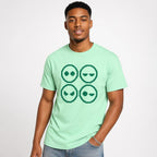 Model wearing an Island Reef T-shirt with a four-panel pixel-art graphic of four alien faces with varied expressions.