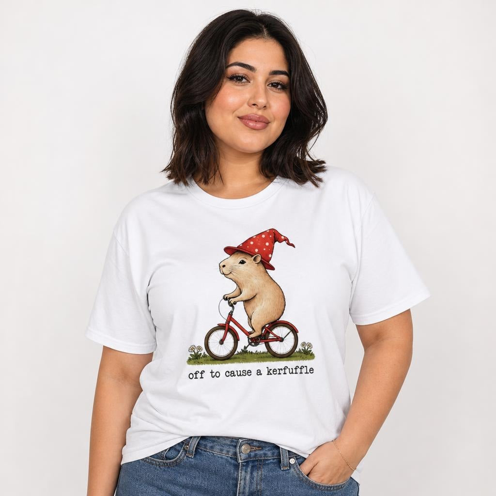 Model wearing a white T-shirt featuring a rat in a red polka-dot hat riding a red bicycle, with flowers, grass, and “off to cause a kerfuffle”.