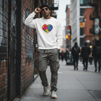 South Asian man wearing a white autism awareness sweatshirt with a rainbow puzzle heart design.
