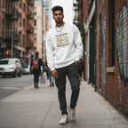 South Asian man wearing a white "We All Thrive Under Different Conditions" autism awareness sweatshirt.