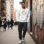 South Asian man wearing a white rainbow heart puzzle sweatshirt.