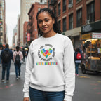 South Asian woman wearing a white autism awareness puzzle heart sweatshirt.