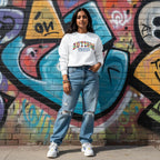 South Asian woman wearing a white autism mama collegiate sweatshirt.