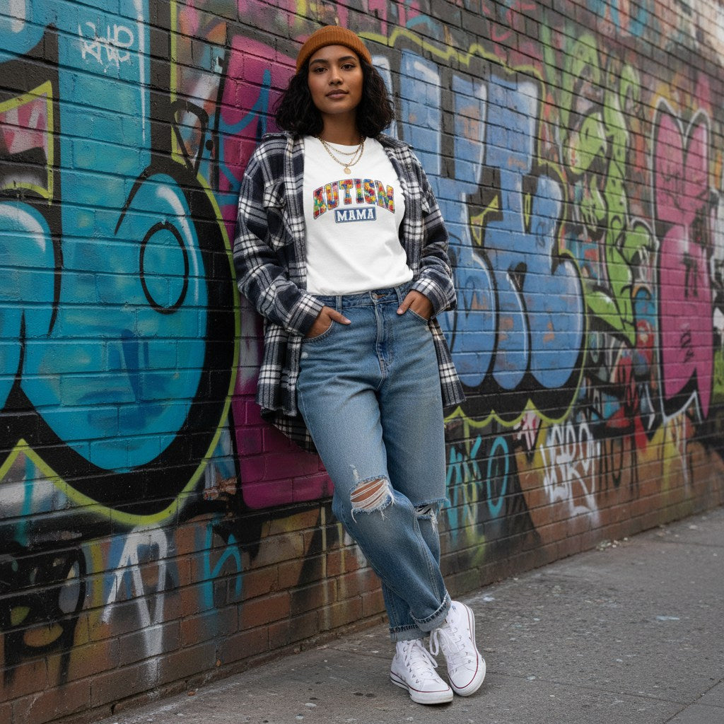 South Asian woman wearing a white Autism Mama collegiate T-shirt.