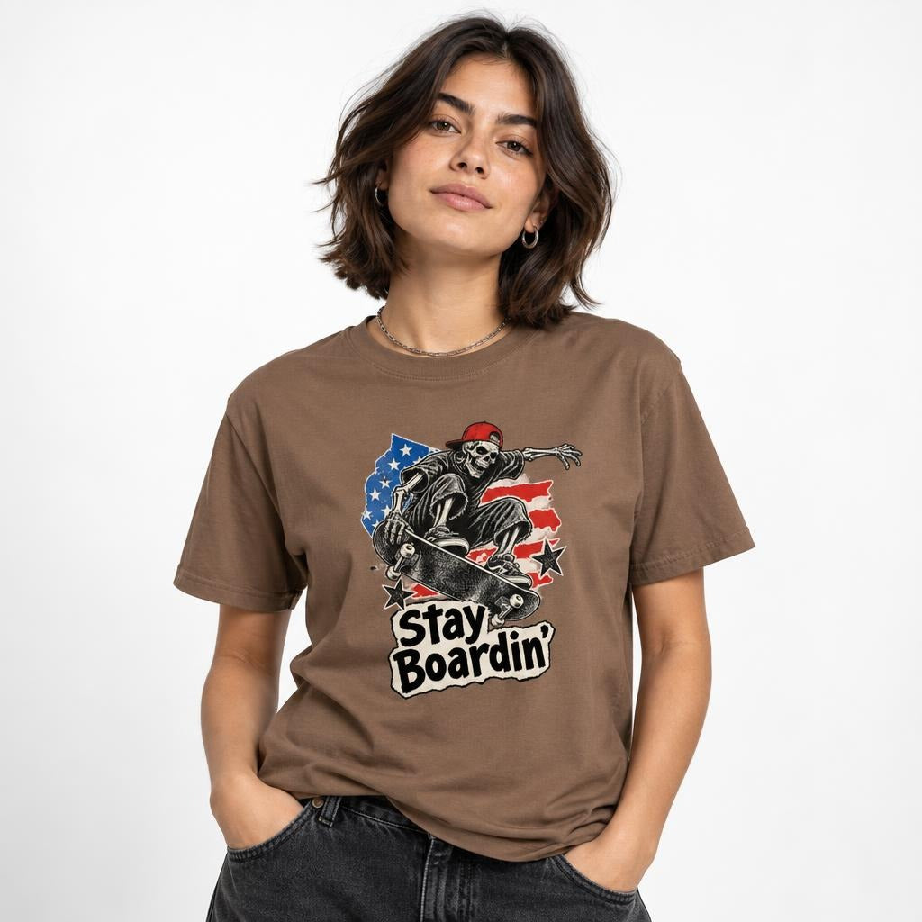 Model wearing an Espresso T-shirt with a front graphic of a skeleton riding a skateboard beneath the text “Stay Boardin'.”